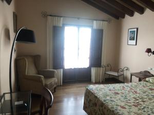 a bedroom with a bed and a chair and a window at Casa Rural Trebol4Hojas in San Pedro