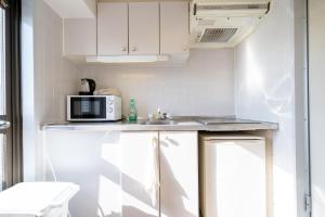 a small kitchen with a microwave and a sink at Nishinippori Guest House in Tokyo