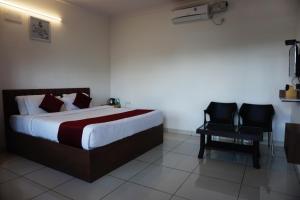 a hotel room with a bed and a chair at Vistar Resort & Hotels in Bangalore