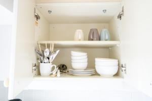 a cupboard with plates and bowls and utensils at Nishinippori Guest House in Tokyo