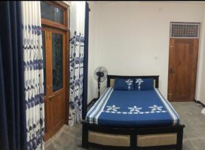 a bedroom with a bed with a blue comforter at La Ventana Guest House Hirikatiya. in Matara