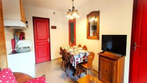 ein Esszimmer mit einem Tisch und einer roten Tür in der Unterkunft Résidence Le Palatin - Appartements pour 6 Personnes 344 in Pelvoux