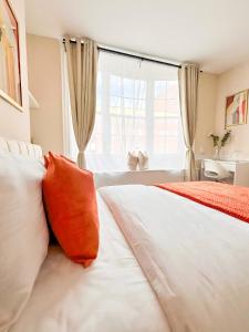 a bedroom with a bed with orange pillows and a window at City Euphoria in Portsmouth