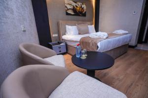 バクーにあるArium Hotel Bakuのベッド、テーブル、椅子が備わるホテルルームです。