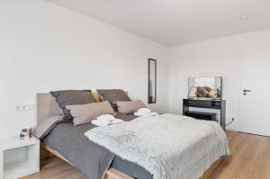 a white bedroom with a bed and a desk at NEU: Stylische Suite mit Ausblick in Sindelfingen