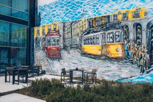 een muurschildering aan de zijkant van een gebouw met tafels en treinen bij Iberostar Selection Lisboa in Lissabon