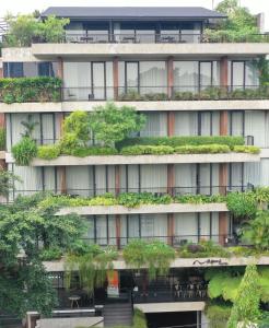 Nagomi Suites & Hotel في جاكرتا: عمارة سكنية يوجد بها نباتات على الواجهة