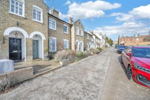 a red car parked in front of a row of houses at Charming Church Walk - 2 bedroom property with parking in Long Melford