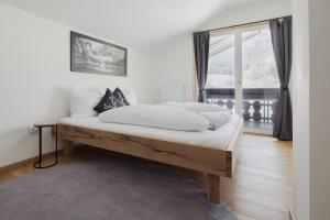 a bedroom with a bed with white sheets and a window at Ferienhaus Streif LXL in Kirchdorf in Tirol