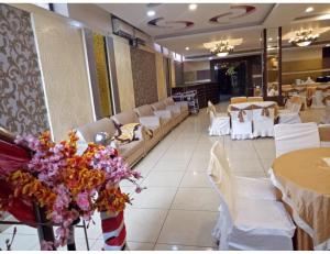 un restaurante con mesas blancas, sillas blancas y flores en Hotel Golden Palm, Gurdaspur, en Gurdāspur