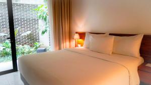 Nagomi Suites & Hotel في جاكرتا: غرفة نوم بسرير ابيض كبير ونافذة