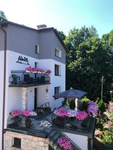 a white building with flower boxes and an umbrella at Villa Almira in Polanica-Zdrój