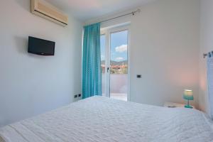 a white bedroom with a bed and a window at Villa Rosanna in Capoterra