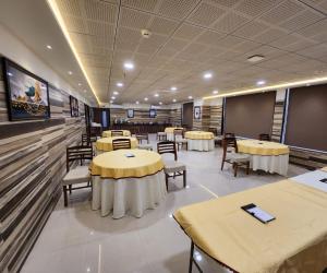 une salle de conférence avec des tables, des chaises et un écran dans l'établissement HOTEL 4ReN, à Bhavnagar