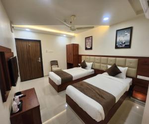 a hotel room with two beds and a television at HOTEL 4ReN in Bhavnagar