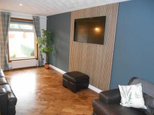 a living room with a leather couch and a stool at Eliburn Woodside Lodge in Livingston