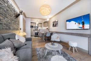a living room with a couch and a tv on a wall at Résidence Carre Blanc - 2 Pièces pour 6 Personnes 424 in Courchevel