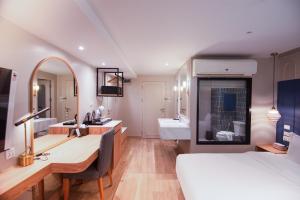 a bedroom with a desk and a bed and a bathroom at THEE Bangkok Hotel by TH District in Bangkok