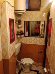 a bathroom with a toilet and a person taking a picture at Deer park Studio Flat (1 BHK) in New Delhi