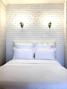 a white bedroom with a white brick wall and a bed at 1-комнатная квартира in Kokshetau