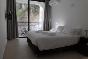 Schlafzimmer mit einem Bett mit weißer Bettwäsche und einem Fenster in der Unterkunft Rifugio Retreat Bed&Breakfast in Kakopetria