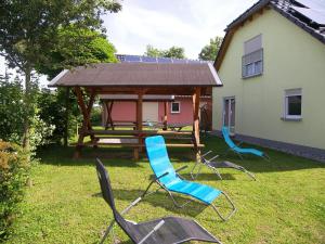 three chairs and a picnic table in a yard with a gazebo at Ferienpark Neppermin Appartmenthäuser in Neppermin