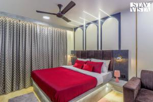 a bedroom with a bed with red pillows and a ceiling fan at StayVista at Cityscape with Rooftop Pool - Jaipur in Jaipur +5 photos