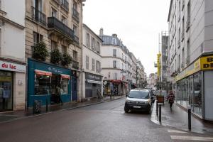 ein Auto, das eine Stadtstraße mit Gebäuden entlangfährt in der Unterkunft COSY, DESIGN AND LUXURY APARTMENT, 5 MINUTS PARIS in Saint-Mandé