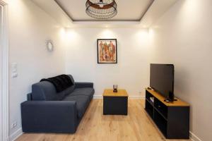 ein Wohnzimmer mit einem blauen Sofa und einem Flachbild-TV in der Unterkunft COSY, DESIGN AND LUXURY APARTMENT, 5 MINUTS PARIS in Saint-Mandé