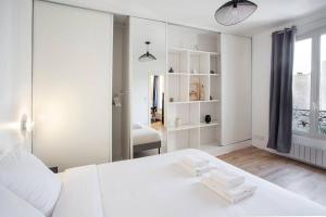 ein weißes Schlafzimmer mit einem weißen Bett und einem Fenster in der Unterkunft COSY, DESIGN AND LUXURY APARTMENT, 5 MINUTS PARIS in Saint-Mandé