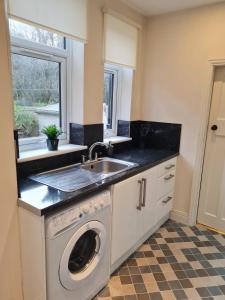 a kitchen with a sink and a washing machine at Genade Apartments - Heaton in Newcastle upon Tyne