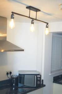 eine Küche mit Arbeitsplatte, Mikrowelle und Beleuchtung in der Unterkunft Cozy Apartment in Birchwood in Risley