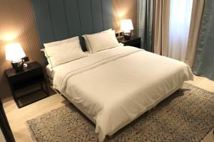 ein großes weißes Bett in einem Schlafzimmer mit zwei Lampen in der Unterkunft Liyaqat Airport Residence in Muscat