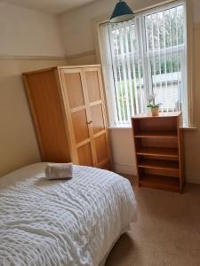 a bedroom with a bed and a dresser and a window at Genade Apartments - Heaton in Newcastle upon Tyne