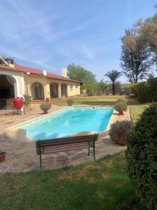 a swimming pool with a bench in front of a house at Khomas Hochland Chalet in Prospect