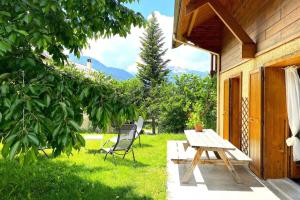 a wooden picnic table and a chair in a yard at CASA-Emmanuelle chalet Guillestre in Guillestre