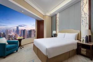 a bedroom with a large bed and a blue chair at Shangri-La Hefei in Hefei