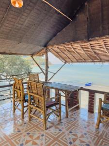 a table and chairs on a patio with a view of the ocean at Full Moon Bungalow Resort Koh Chang Ranong in Koh Chang Ranong