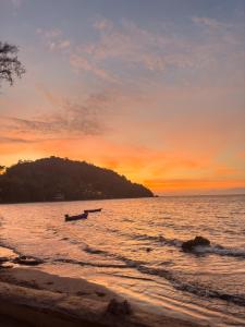 a boat in the water on the beach at sunset at Full Moon Bungalow Resort Koh Chang Ranong in Koh Chang Ranong