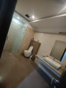 La salle de bains est pourvue de toilettes, d'un lavabo et d'un miroir. dans l'établissement Urbanized Comfy Apartment, à Rawalpindi