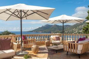 a patio with two chairs and two umbrellas at Tiara Yaktsa Côte d’Azur in Théoule-sur-Mer