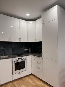 una cocina blanca con armarios blancos y fregadero en OZO Life Apartment en Vilna