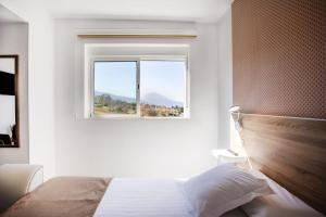 a white bedroom with a bed and a window at Casa Senderos del Norte in Sauzal