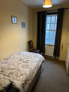 a bedroom with a bed and a chair and a window at Barley Mow Hotel in Pontefract