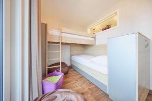 een kleine slaapkamer met een stapelbed en een stapelbed bij Nordico, FeWo 8 in Duhnen