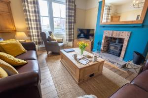 een woonkamer met een bank en een open haard bij Pebble Cottage in Seahouses