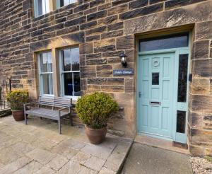 a bench in front of a brick building with a blue door at Pebble Cottage by Coast & Country Stays in Seahouses