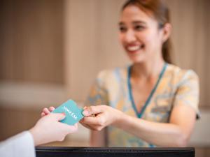 een vrouw geeft een creditcard aan een andere vrouw bij M Social Hotel Phuket in Patong Beach