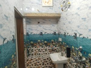 a bathroom with a sink and penguins on the wall at Stay With Us Home Stay in Jaisalmer