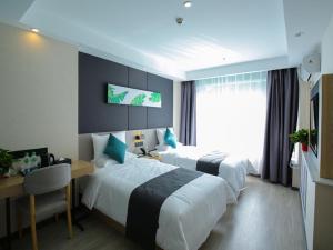 a hotel room with two beds and a desk and a desk at Thank Inn Chain Xianyang Renmin Road Central Plaza in Xianyang